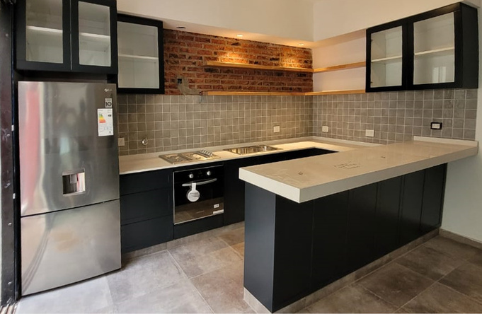 Cocina remodelada con muebles oscuros, mesada de cemento e isla